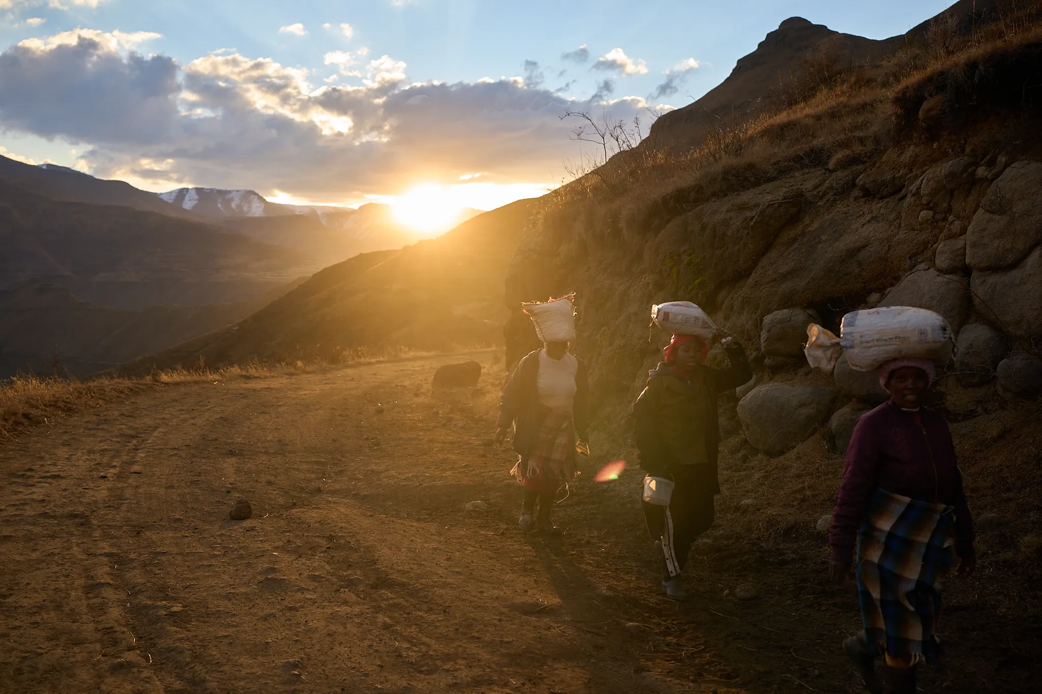 Women carry bags of food in the mountains of Ha Lejone, Lesotho