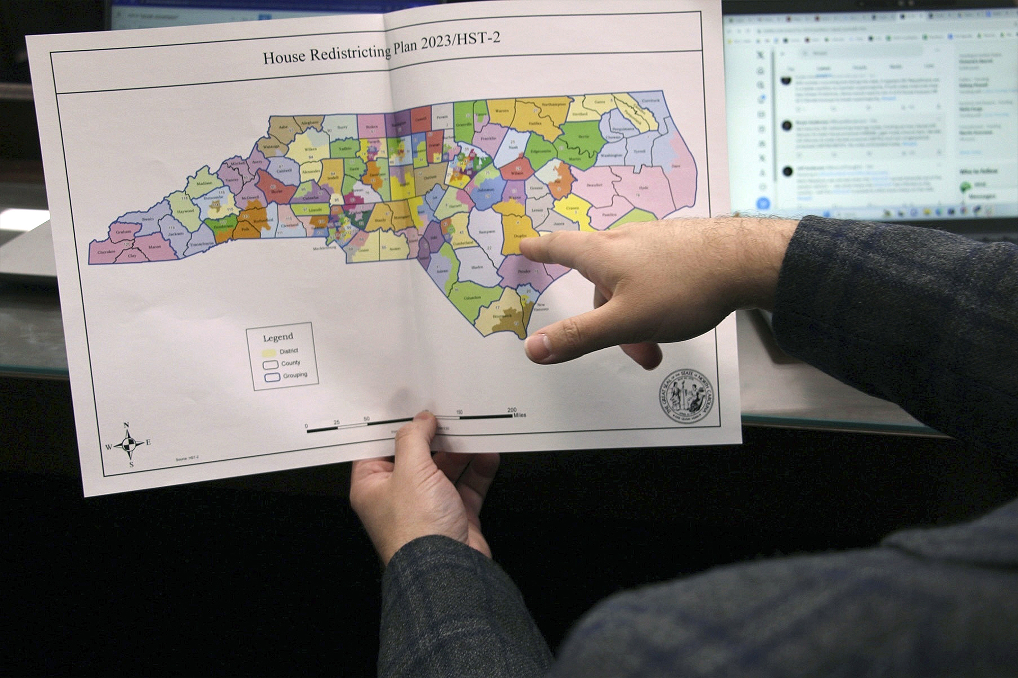 Person pointing at a map showing new state house districts