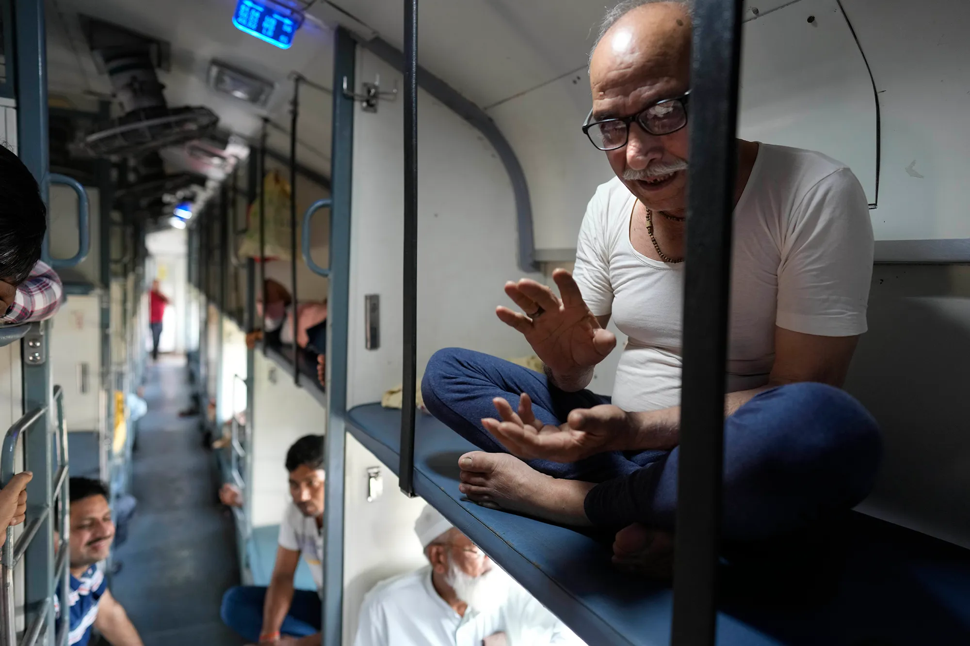 A man sitting on a bench on an Indian train.
