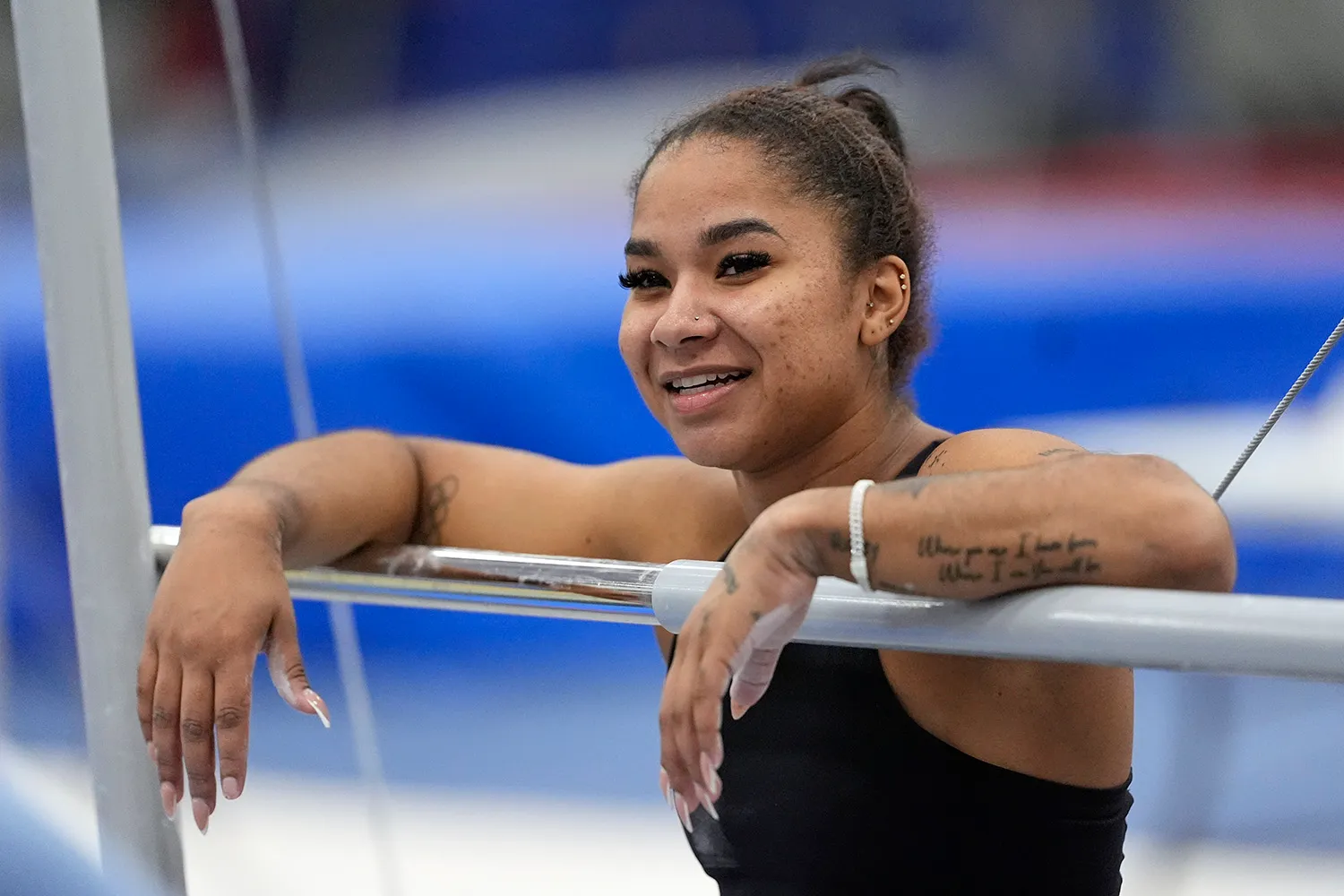 Gymnast Jordan Chiles smiling and leaning on a bar.