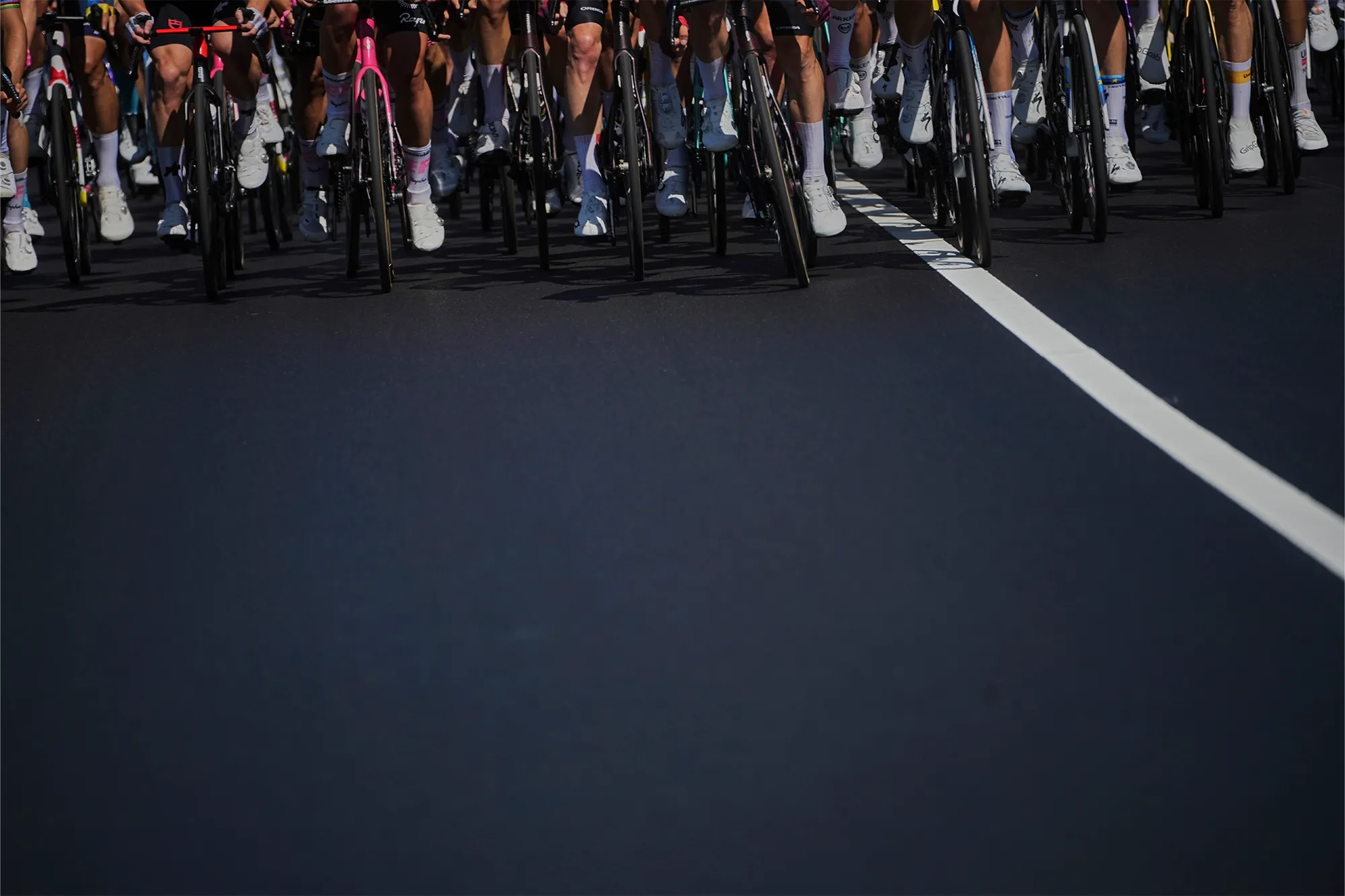 Bottom half of a pack of cyclists on a road