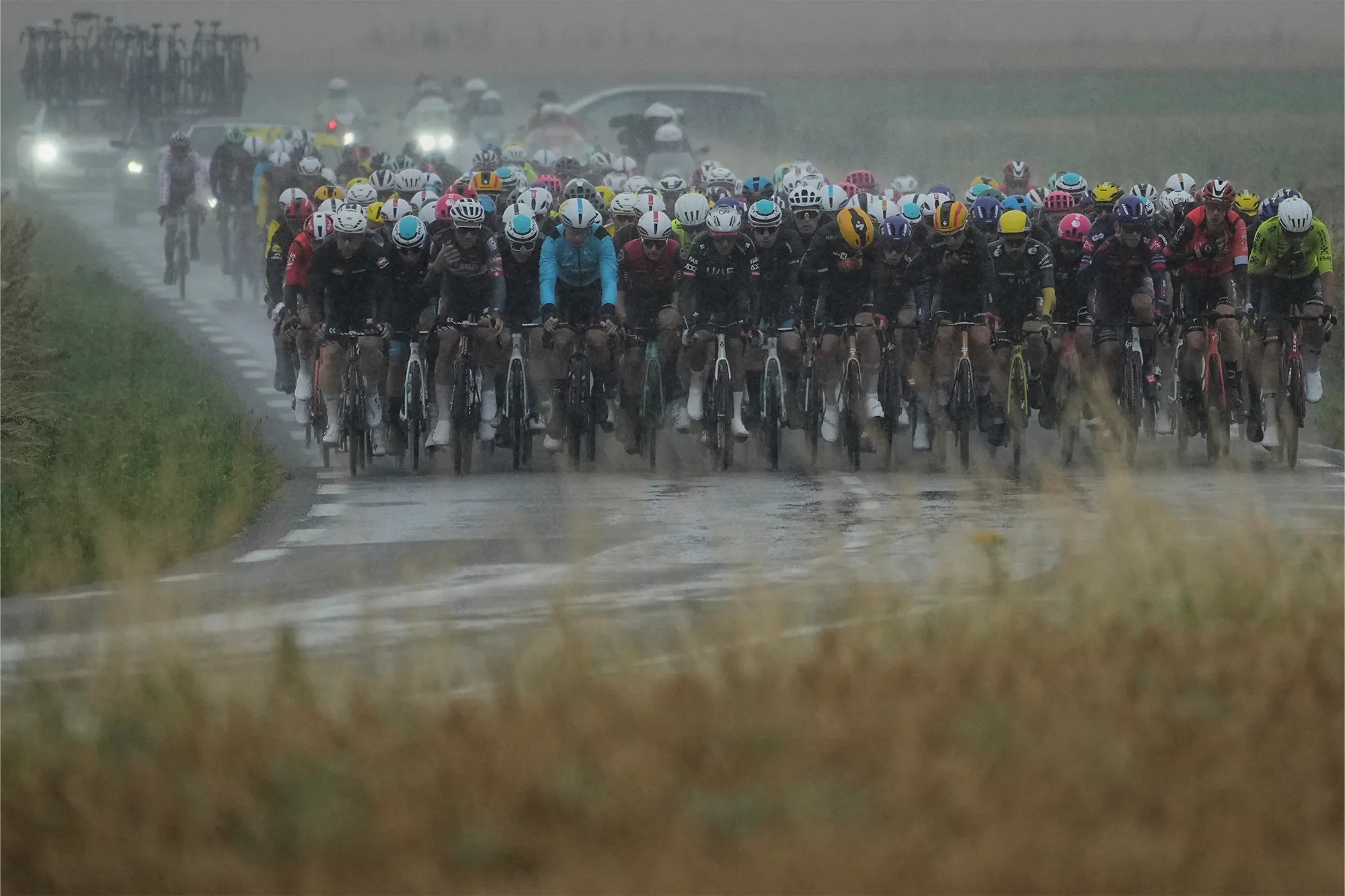 A pack of cyclists riding in the rain